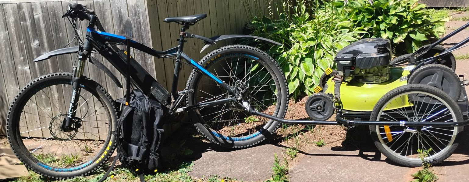 An image of an electric bike with a trailer holding a lawnmower